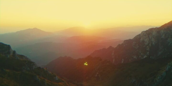 Aerial cinematic view of rocky mountain peaks near Tiganesti refuge in Bucegi Mountains at sunset