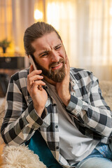 Man at home pressing cheek in hard tooth pain, quickly dialing phone for immediate dentist contact....