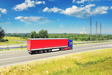 A truck driving through a landscape under high voltage pylons