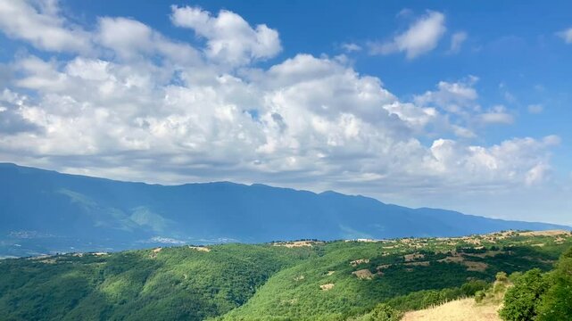 Timelapse of cumulus clouds moving in the blue sky above the mountains