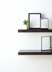 Floating dark wood shelf mounted on white wall, styled with two modern photo frames in black and...