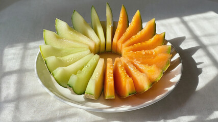 Neatly Arranged Cantaloupe and Honeydew Slices on Ceramic Platter