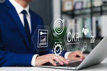 OKR Objectives and Key Results Business Strategy Concept. Businessman using laptop with OKR icons,...