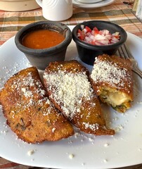 three golden-brown savory pastelitos y queso and chaya at a cafe in Mexico