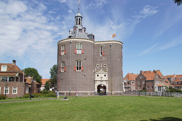 Drommedaris is the southern gateway of the Dutch city Enkhuizen. Grass, blue sky, houses. Summer, July, Netherlands 