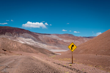 Desert road curve with yellow sign