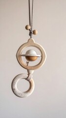Wooden Baby Rattle with Hanging Circles and Knitted Cord on Beige Background