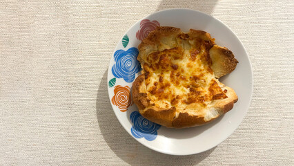 Garlic bread with melted cheese resting on a colorful plate
