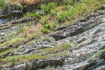 Rock of layered stone overgrown with grass and moss.