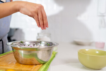 Chef adding salt to peruvian ceviche in modern kitchen