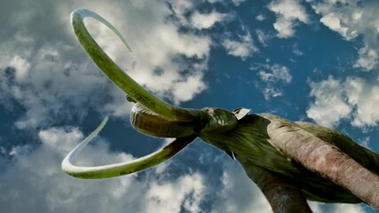Low-angle view of a towering mammoth model, its massive form silhouetted against a clear blue sky