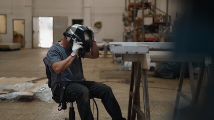 Welder checking welding gear inside industrial metalworking facility