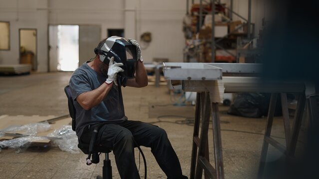 Welder checking welding gear inside industrial metalworking facility