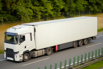 White Modern Sustaianble Refrigeration Transporter, Euro Semi Truck on Highway Near Forest &ndash; Fast Freight Transport Concept