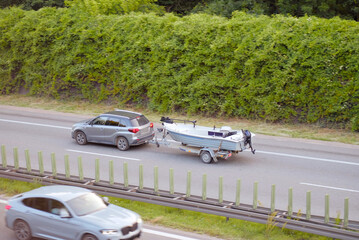 Fototapeta premium SUV Towing Fishing Boat on Highway – Summer Outdoor Adventure Travel Scene
