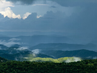 sunlight shining on a mountain with surrounding mountains in shadow