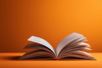 An open book rests on a vibrant orange background, providing ample copy space. The scene is beautifully lit, showcasing intricate details and textures in a warm, inviting atmosphere.