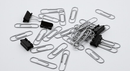 Assorted Silver Paper Clips and Black Binder Clips on White Background