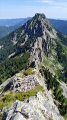 Obraz premium Sharp Mountain Ridge with Green Trees and Clear Blue Sky on Sunny Day