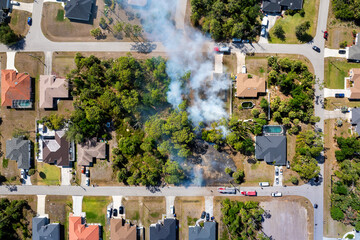 Firefighters battle a fast moving wildfire in Florida forest near suburban homes with fire trucks...