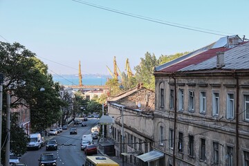 Old residential buildings with wires and street view leading to port cranes and sea