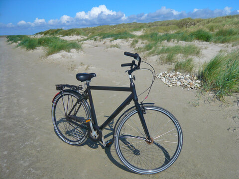Bicycle parked on a sandy beach by sand dunes, Fanoe Bad, Fanoe, Jutland, Denmark