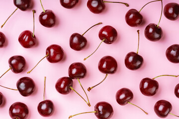 Close up of red raw fresh sweet cherries on pink background. Macro view emphasizing texture, juiciness, and freshness for food designs, health eating, wallpaper, backdrop