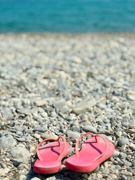 Close-up of a pair of worn pink flip flops on a pebble beach by water's edge, Menton, Alpes-Maritimes, Provence-Alpes-Cote d'Azur, France