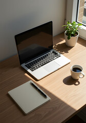 Fototapeta premium Workspace with Laptop Coffee Plant and Notebook in Natural Light