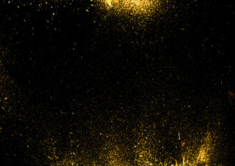 Gold paint splatter on black background. Abstract spray effect overlay. Dusty particle backdrop. Grainy and dusty graphic element layout.