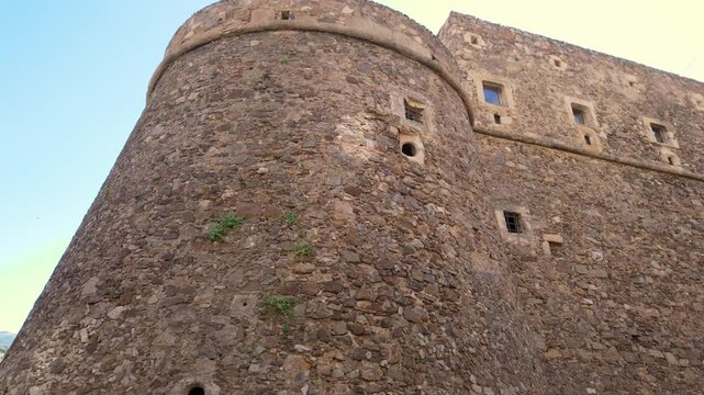 Ancient stone walls and circular tower of Murat Castle rising against blue sky in Pizzo, Calabria, Italy
