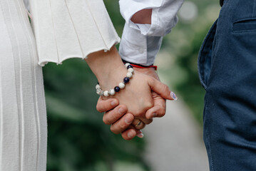 close-up view of couple holding hands, young beautiful caucasian man and woman take each other hands, walking on pathway in park in summer, love and family concept, selective focus