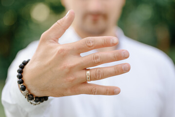 groom in white shirt shows wedding ring, selective focus