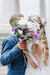 bride and groom kissing each other, shielding with bouquet