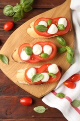 Tasty sandwiches with mozzarella cheese, tomatoes and basil on wooden table, flat lay