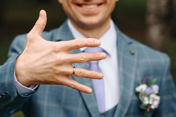 groom in white shirt shows wedding ring, selective focus