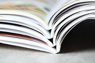 Different open magazines on grey table, closeup
