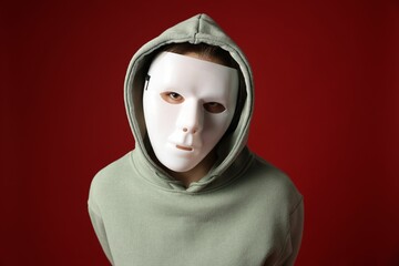 Anonymity. Woman wearing mask on dark red background
