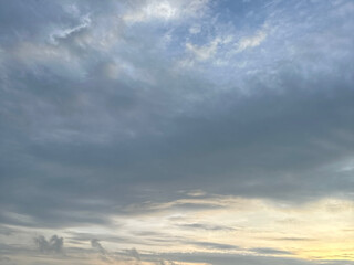 Minimalist sky scene with soft clouds during sunrise, featuring subtle yellow and blue tones. 