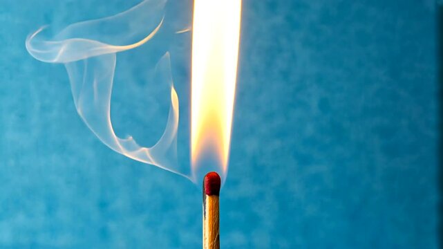 Close-up of a lit matchstick with a vibrant flame against a textured blue background