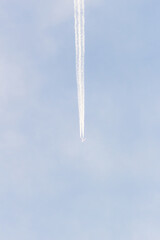 Fototapeta premium Airplane trail in the blue sky with white clouds