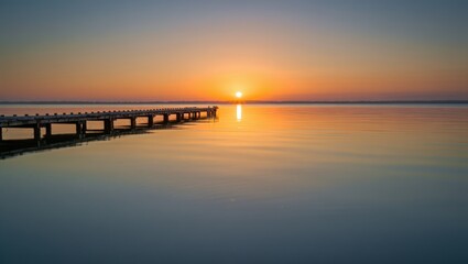Obraz premium Serene Pier Reflects Golden Sunrise Over Calm Water