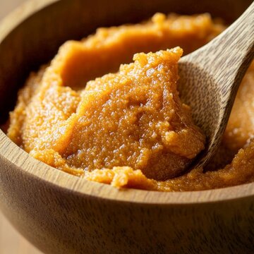 closeup of miso paste in wooden bowl with spoon textured golden brown fermentation detail macro Japanese ingredient photography clean light