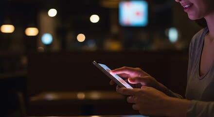 Woman using smartphone in dimly lit cafe, illuminated by screen glow and bokeh lights
