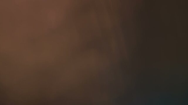 Abstract cinematic light leak overlay with subtle lens flare effects on dark background, creating organic film burn and bokeh for video editing