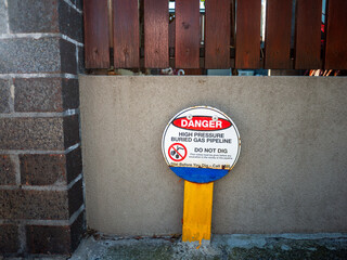 Warning sign indicating a high-pressure buried gas pipeline in a suburban street in Australia. The...