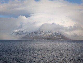 Moody storm clouds over snowy mountains and calm arctic water