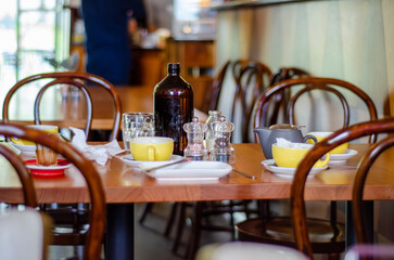 An uncleared cafe table showing the aftermath of breakfast, with half-finished drinks, used cups,...