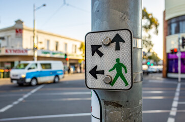 A pedestrian directional crossing sign shows arrows for multiple crossing directions with a green...