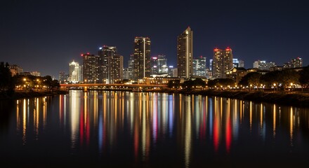 Obraz premium Nighttime Cityscape Reflection: Illuminated Skyscrapers and River Reflections.